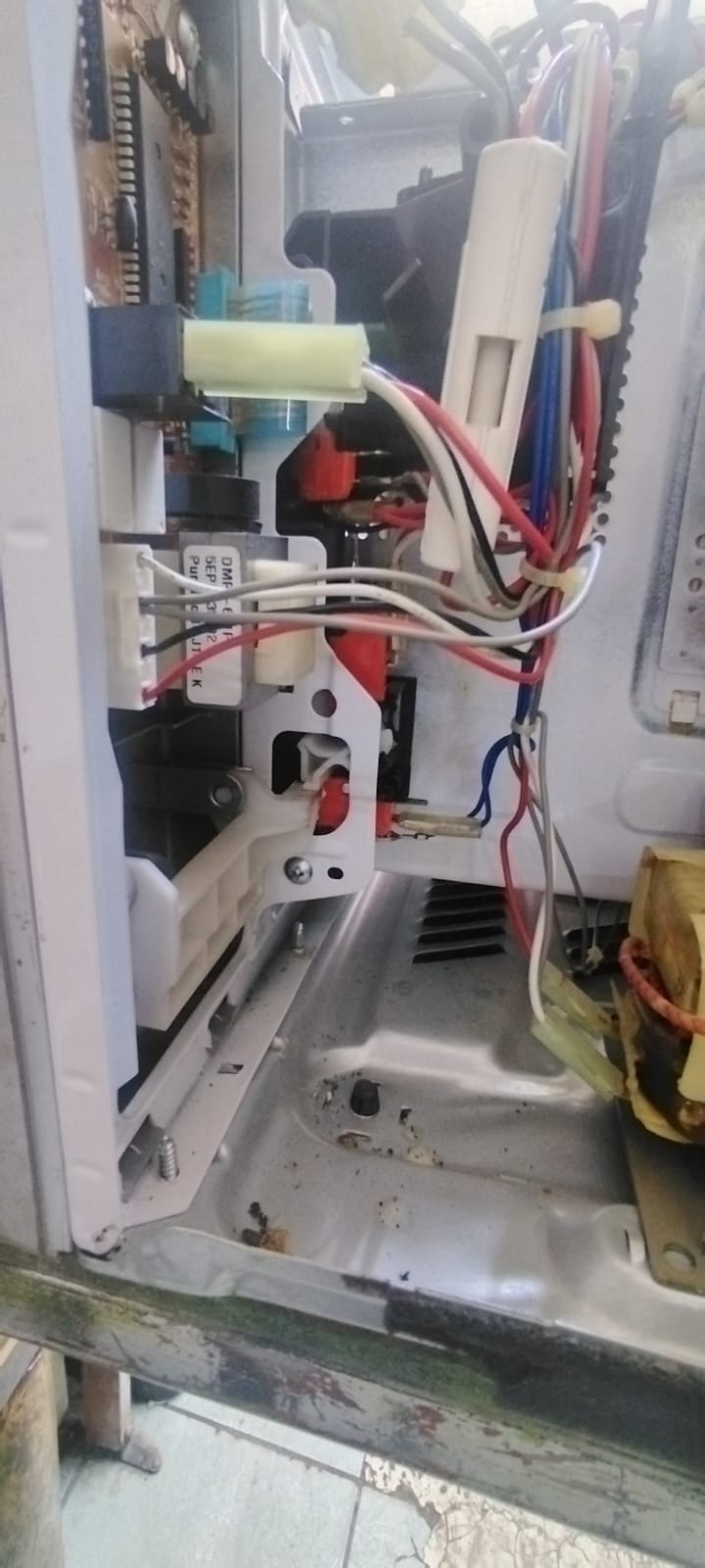 Interior del microondas mostrando la tarjeta electrónica, relevadores y arnés de cables durante la revisión