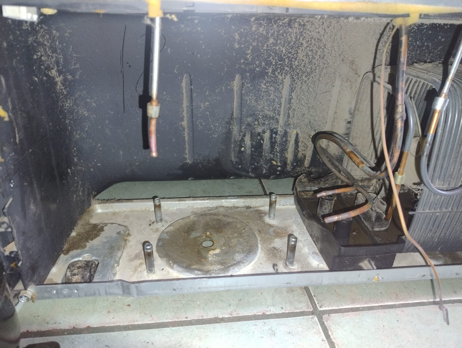 Base trasera del refrigerador sucia después de retirar el compresor dañado